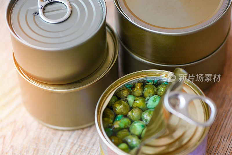 罐头食品在金属罐头木质背景上，俯视图/罐头食品不易腐坏的食品储存在厨房的家用罐头豌豆